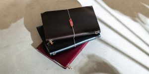 Tres notāre Muse con charms apilados sobre suelo claro, con sombras.