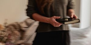 Persona caminando por un interior con movimiento desenfocado, sosteniendo un journal de cuero oscuro con páginas claras.