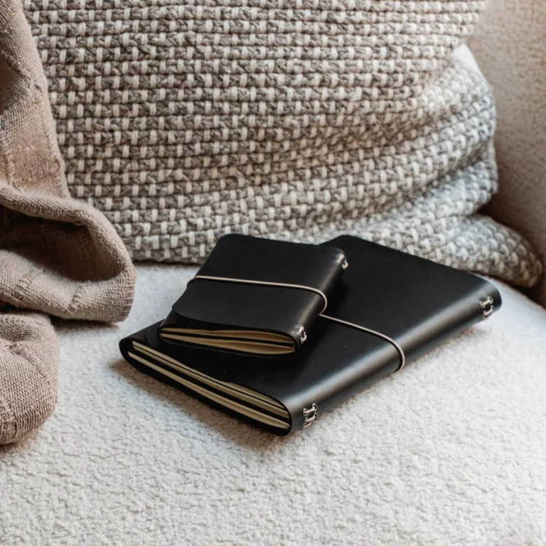 Muse y Nomad, journals de cuero negro apilados sobre un sofá