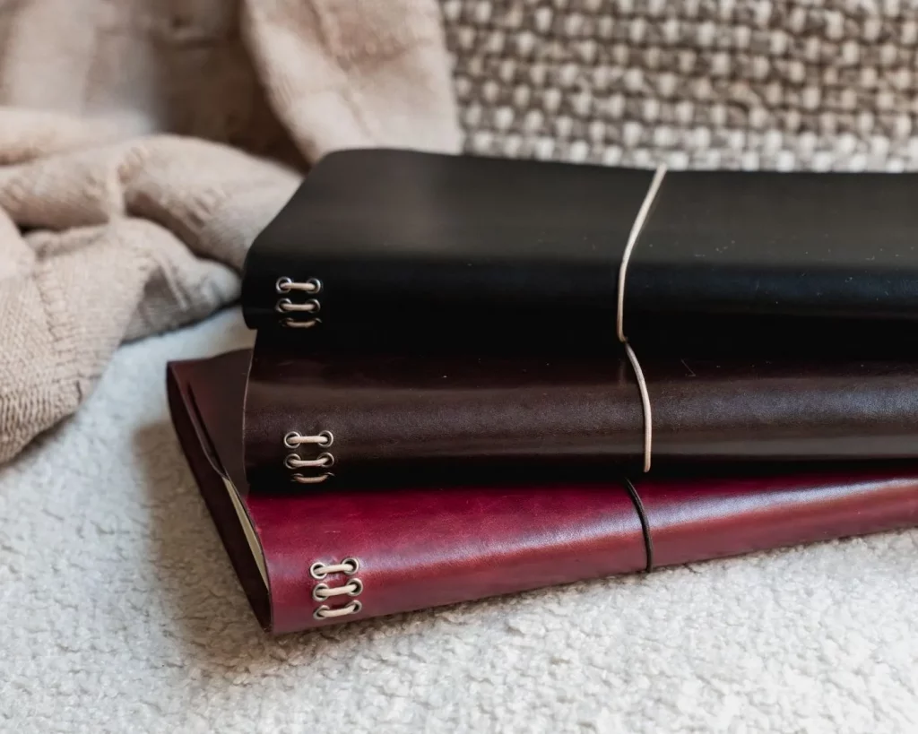 Journals de cuero notāre apilados en sofá, detalle de elásticos