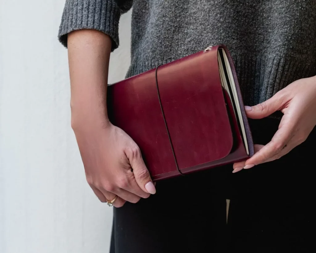 Manos sosteniendo un journal de cuero notāre muse burgundy